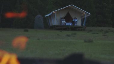 Bir adam ve bir kadın balkonda oturmuş ateşin yanmasını izliyorlar.