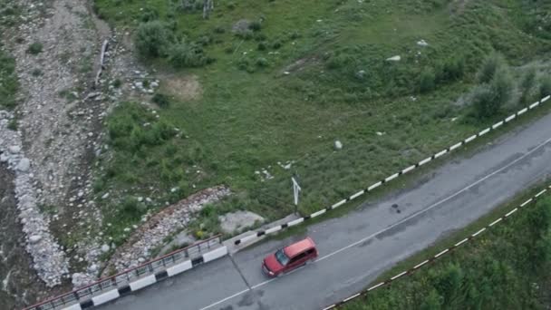 Vista aérea de cima para baixo 4K de um carro vermelho dirigindo em uma estrada rural na floresta — Vídeo de Stock