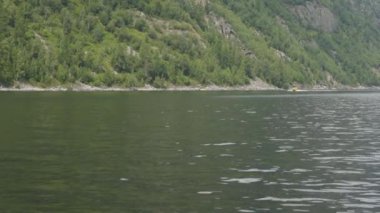 Shooting from a motor boat bobbing on the waves, a view of a passing yellow boat