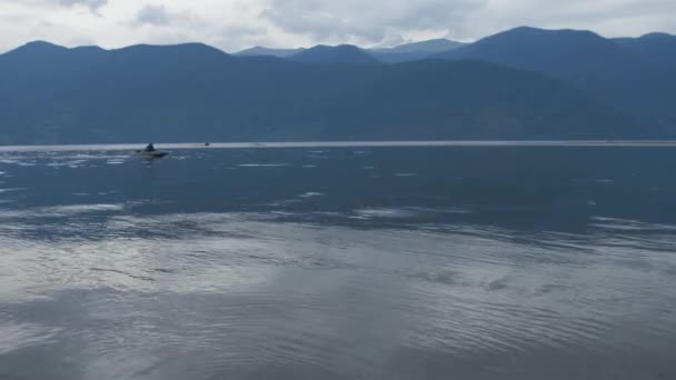 Łódź motorowa pływa po jeziorze na tle gór przy złej pogodzie — Wideo stockowe