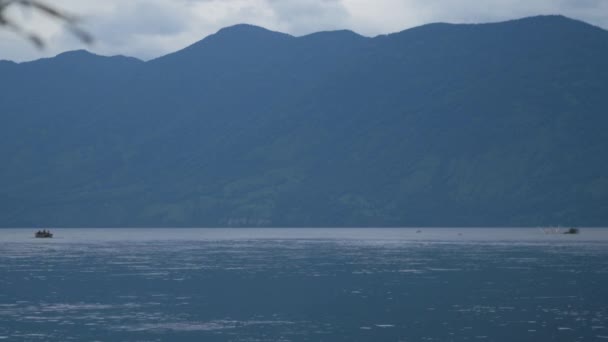 Bateau à moteur navigue sur le lac sur fond de montagnes par mauvais temps — Video