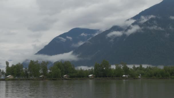 Tienda de campaña ciudad en el río Banco sobre el fondo de montañas, nubes y niebla — Vídeos de Stock