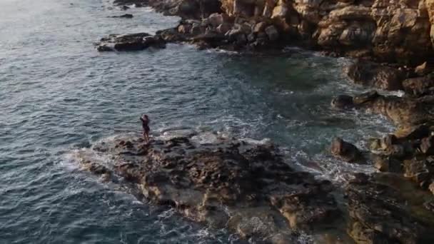 Аэрофотосъемка, как девушка танцует на мысе, скале, морском берегу 4k — стоковое видео