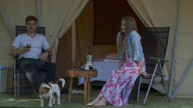 Sandalyede oturan, konuşan, kahve içen, köpekle oynayan bir çift.