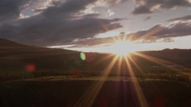 Güneş ışınları dağlardaki bulutları delip geçiyor. Turuncu gün batımı. 4K.