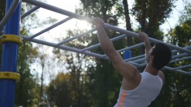 Şehir Parkı içinde yatay çubuk vücudunda kaldırma yapan atletik erkek. Erkek sporcu egzersiz sırasında açık güç egzersizleri gerçekleştirir. Genç adam statik egzersiz gösterir. Eğitim dışında