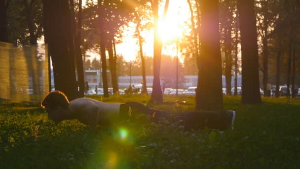 Erkek atlet itme yapıyor ups açık atlama ile. Genç adam egzersiz günbatımı şehir parkında. Sporcu eğitim dışında arka plan güzel güneş doğarken, yakın çekim. Ağır çekim. — Stok video