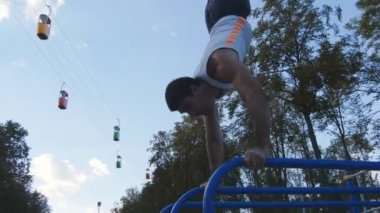 Güçlü kas adam amuda bir parkta. Kaslı erkek spor adamı yatay çubuklarında açık stunts yapıyor. Sporcu eğitim kas dışında bir hareketten gerçekleştirir. Egzersiz spor yaşam tarzı
