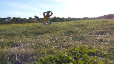 Yoga oturan genç adam çayır yeşil çim, poz ve derin derin düşünür. Kaslı adam lotus poz doğa, rahatlatıcı. Eğlence güneşli gün açık. Arka plan, güzel manzara. Yakın çekim