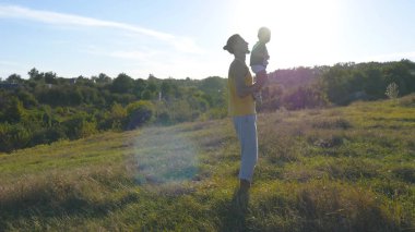 Doğa onun çocuğuna oynayan genç baba. Baba oğlu holding bacaklar ve açık atar. Mutlu bir aile birlikte dışarıda çayır vakit. Arka plan, güzel manzara. Yakın çekim