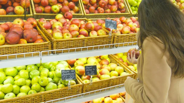 Женщина выбирает свежие красные яблоки в продуктовом отделе и кладет их в пластиковый пакет. Молодая красивая девушка выбирает яблоки в супермаркете и положить их в корзину магазина. Закрыть — стоковое фото