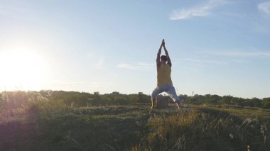Yoga poz açık ayakta sportif delikanlı. Beyaz adam pratik Yoga hamle ve doğada konumlandırır. Dengeleme atlet. Güzel manzara arka plan olarak. Sağlıklı aktif yaşam tarzı