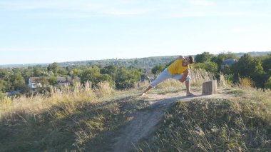Ayakta yoga poz, doğa, genç adam. Adam pratik yoga hamle ve açık havada konumlandırır. Hill gücü egzersiz yaparak atlet. Arka plan manzara. Sağlıklı aktif yaşam tarzı. Yakın çekim