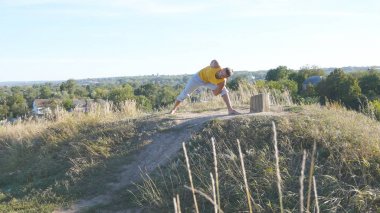 Ayakta yoga poz, doğa, genç adam. Adam pratik yoga hamle ve açık havada konumlandırır. Hill gücü egzersiz yaparak atlet. Arka plan manzara. Sağlıklı aktif yaşam tarzı. Yakın çekim