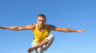 Sportif delikanlı ağaç yoga poz arka plan olarak mavi gökyüzü ile ayakta portresi. Beyaz adam pratik Yoga hamle ve doğada konumlandırır. Tek ayak üstünde Dengeleme atlet. Sağlıklı aktif yaşam tarzı
