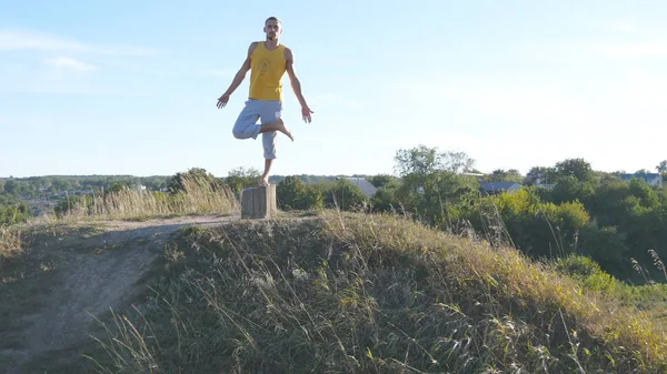 Sportos férfi állva fa jóga pózol kültéri. Yogi gyakorló jóga mozog és pozíciókat a természetben. Sportoló egyensúlyozása az egyik lábon. Gyönyörű természet, mint a háttér. Egészséges, aktív életmód — Stock Fotó