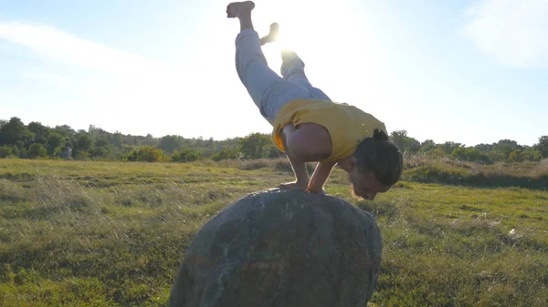 Junger sportlicher Mann, der schwierige fortgeschrittene Yoga-Pose in der Natur praktiziert. Kaukasischer Typ, der Yogabewegungen und Positionen im Freien macht. schöne Landschaft im Hintergrund. gesunder aktiver Lebensstil. Nahaufnahme — Stockfoto