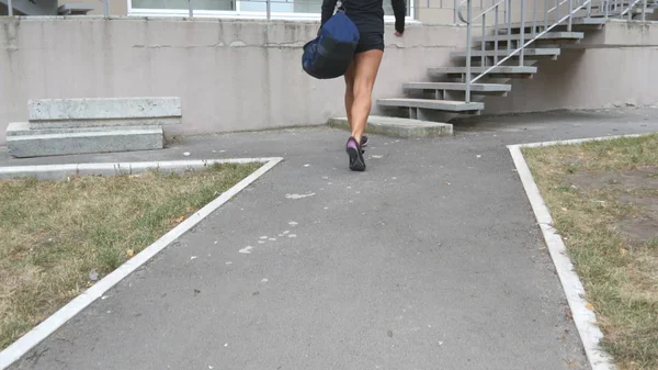 Joven mujer de fitness en ropa deportiva subiendo escaleras hasta el gimnasio para entrenar. Una chica va a un club de salud para hacer ejercicio. De cerca. —  Fotos de Stock