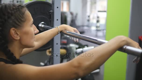 Portret van de jonge vrouw zich voorbereidt op het heffen van zware halters in de sportschool. Vrouwelijke atleet een barbell met zware gewichten op haar schouders nemen. Slow motion — Stockvideo