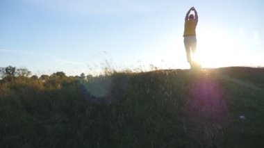 Genç adam pratik Yoga hamle ve hill adlı günbatımında konumlandırır. Sportif adam yoga poz doğada ayakta. Güzel manzara arka plan olarak. Yogi açık, sağlıklı aktif yaşam tarzı. Ağır çekim
