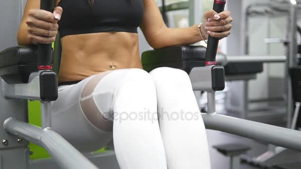 Jonge sterke vrouw met perfecte fitness lichaam in sportkleding uitoefening van buikspieren in sportschool. Prachtige vrouwelijke torso met piercings bij de navel. Meisje opleidingen - heffen van de benen. Slow-motion. Close-up. — Stockvideo