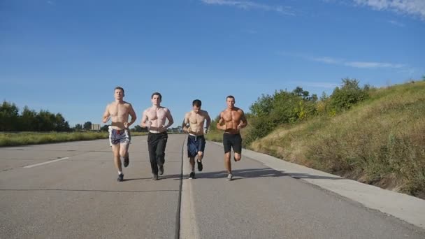 Un grupo de corredores trotando en la autopista. Los atletas deportivos masculinos entrenan al aire libre en verano. Jóvenes chicos musculosos fuertes haciendo ejercicio en la carretera rural durante el entrenamiento juntos. Estilo de vida activo. Movimiento lento — Vídeos de Stock