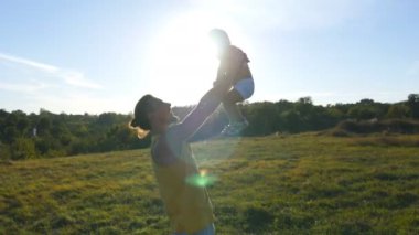 Küçük oğlu ile açık oynayan genç baba. Baba çocuğunu doğa, yukarı kaldırma. Mutlu bir aile birlikte dışarıda çayır vakit. Arka plan, güzel manzara. Yakın çekim