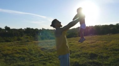 Küçük oğlu ile açık oynayan genç baba. Baba çocuğunu doğa, yukarı kaldırma. Mutlu bir aile birlikte dışarıda çayır vakit. Arka plan, güzel manzara. Yakın çekim
