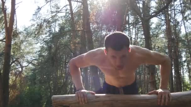 Homme athlétique faisant des pompes à partir du journal de bord à la forêt. Jeune homme musclé fort s'entraînant en plein air au bois en été. Athlète faisant de l'exercice dans une belle nature. Entraînement mode de vie sain. Gros plan — Video