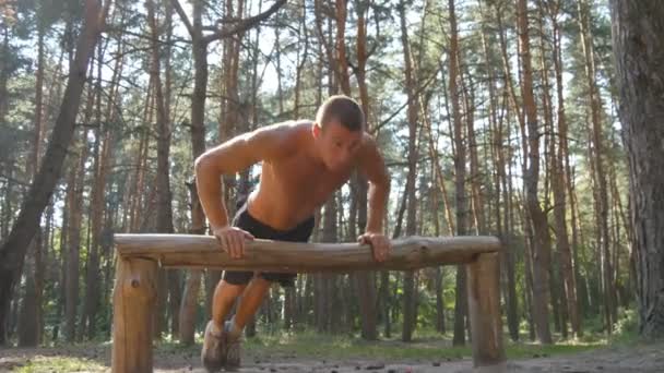 Homme athlétique faisant des pompes à partir du journal de bord à la forêt. Jeune homme musclé fort s'entraînant en plein air au bois en été. Athlète faisant de l'exercice dans une belle nature. Entraînement mode de vie sain. Gros plan — Video