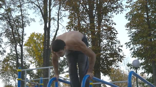 Güçlü kas adam amuda bir parkta. Kaslı erkek spor adamı yatay çubuklarında açık stunts yapıyor. Sporcu eğitim kas dışında bir hareketten gerçekleştirir. Egzersiz spor yaşam tarzı — Stok video