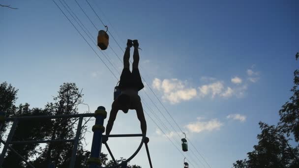 Silný svalnatý muž dělá stojky v parku. Přizpůsobit svalnatý muž fitness chlap dělá senzace na vodorovných pruhů venkovní. Atletka, školení provádí stojka na svalu mimo. Trénink Sportovní životní styl — Stock video