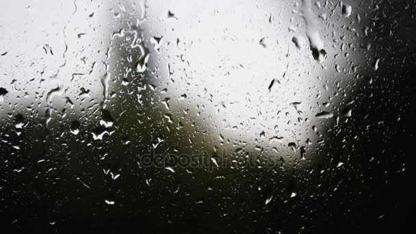 Primer plano de las gotas de agua en el vidrio. Gotas de lluvia sobre vidrio de ventana con fondo borroso. Árbol borroso y cielo. Días lluviosos, lluvia corriendo por la ventana, bokeh — Vídeos de Stock