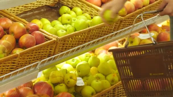 Manos masculinas seleccionando manzanas frescas en el departamento de productos de comestibles y poniéndolo en la cesta. Chico joven está eligiendo frutas en el supermercado y ponerlos en el carrito de la compra — Vídeos de Stock