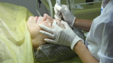 Yaşlı kadın yalan ve Başlarken kaşları makyaj Güzellik Salonu. Kalıcı hale kirpik üzerinde uygulanması. Kalıcı makyaj kirpik yapma güzellik uzmanı. Kaşları ile ana çalışır. Yarı kalıcı makyaj