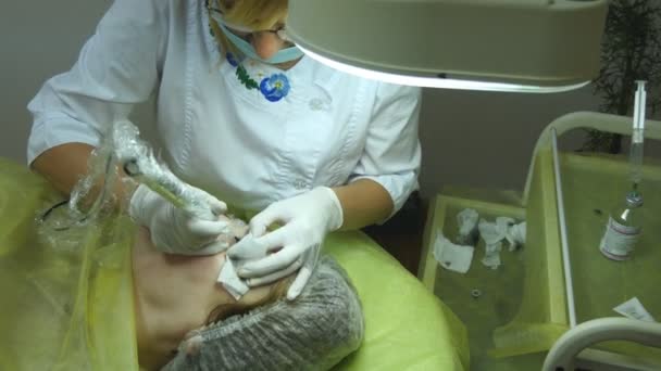 La anciana miente y consigue maquillaje de pestañas en el salón de belleza. Aplicar maquillaje permanente sobre la pestaña. esteticista haciendo maquillaje permanente de pestañas. El maestro trabaja con las cejas. Maquillaje semipermanente — Vídeos de Stock