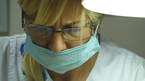 Close-up portret van vrouwelijke arts in glazen met beschermende werk slijtage. Vrouwelijke gezicht in medische masker. Schoonheidsspecialist of therapeut werkt — Stockvideo