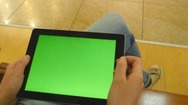 Genç kız alışveriş merkezi tezgah, oturmak ve tablet ile çalışma. Tablet pc ile yeşil ekran kullanarak eller. Chroma anahtar