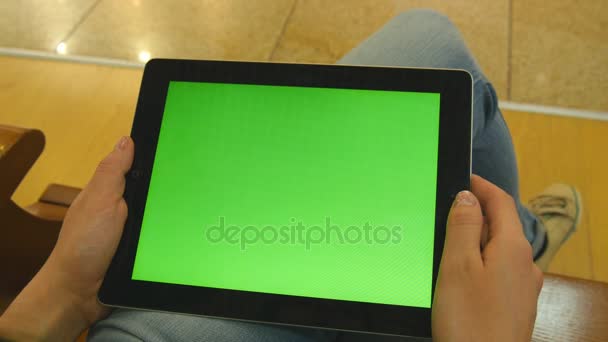 Chica joven sentada en el banco en el centro comercial y trabajando con la tableta. Manos femeninas usando tableta PC con pantalla verde. Clave de croma — Vídeos de Stock