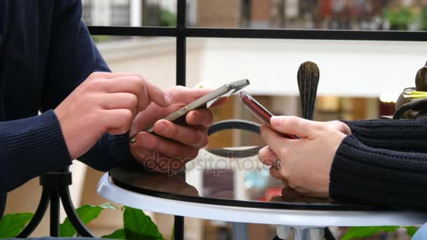 Hands of couple using smartphones together at cafe in shopping mall. Close-up of man and woman browsing information and scrolling pictures on smart phone — Stock Video