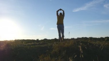 Sportif adam poz yoga açık ayakta silüeti. Yogi Yoga uygulamak hareket eder ve doğal olarak konumlandırır. Güzel gökyüzü ve güneş arka plan olarak. Sağlıklı aktif yaşam tarzı