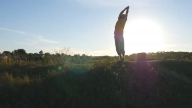 Sportif adam poz yoga açık ayakta silüeti. Yogi Yoga uygulamak hareket eder ve doğal olarak konumlandırır. Güzel gökyüzü ve güneş arka plan olarak. Sağlıklı aktif yaşam tarzı