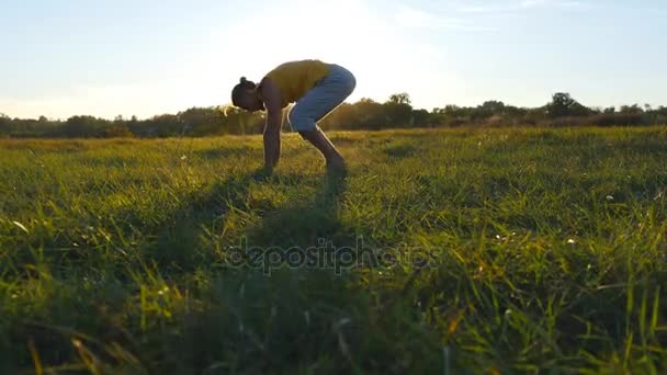 Ung sportig man öva handstående yogaställning på naturen. Kaukasiska killen gör yoga flyttar och positioner utomhus. Vackra landskapet och himlen i bakgrunden. Hälsosam aktiv livsstil. Närbild — Stockvideo