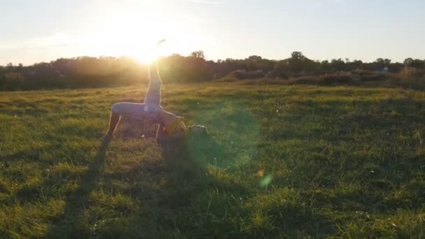 Genç adam pratik Yoga hamle ve yeşil ot, çayır, konumlandırır. Sportif adam yoga poz doğada ayakta. Güzel manzara arka plan olarak. Yogi açık, sağlıklı aktif yaşam tarzı — Stok video