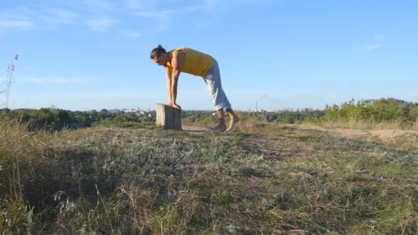 Young sporty man practicing difficult advanced yoga pose at nature. Caucasian guy doing yoga moves and positions outdoors. Beautiful landscape at background. Healthy active lifestyle. Close up — Stock Video