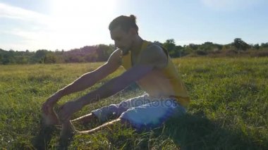 Doğa vücudu germe kas adam. Çayır ve yoga egzersiz yaparak yeşil çim oturan genç adam. Güneşli gün açık eğitim. Arka plan, güzel manzara. Yakın çekim