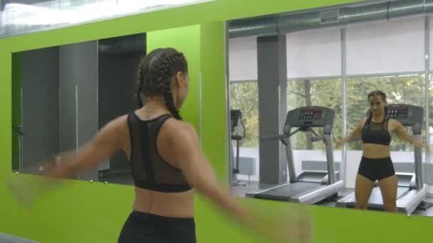 Mujer entrenando frente al espejo en el gimnasio. Atleta femenina estirando su cuerpo y manos antes del entrenamiento. Ejercitantes de chicas en el gimnasio. De cerca. — Vídeo de stock