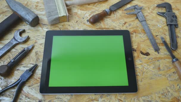 Male hand of artisan craftsman using tablet pc with green screen in workshop. Top view. Different vintage tools lie beside — Stock Video