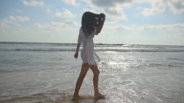 Çıplak ayakla Okyanusu yakınlarındaki sahilde suda yürüyen mutlu kadın. Genç güzel kız hayattan zevk ve sahil eğleniyor. Yaz tatili ya da tatil. Arka plan, doğa manzara. Slowmotion