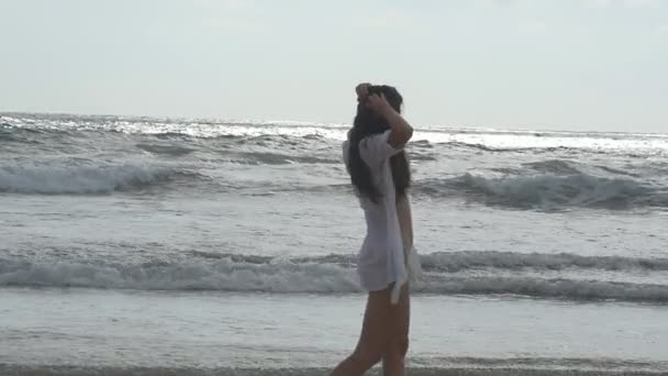 Szczęśliwa kobieta spaceru i grać na plaży, w pobliżu oceanu. Młode piękne dziewczyny cieszyć się życiem i zabawy w brzegu morza. Letni urlop lub wakacje. Egzotyczny krajobraz w tle. Zwolnionym tempie — Wideo stockowe